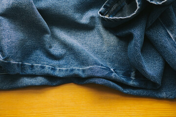 Fototapeta premium Close up of dark blue denim jeans on wooden background. Denim texture on wooden background