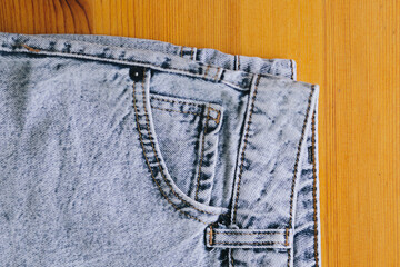 Close up of front pocket of jeans. Denim texture on wooden background