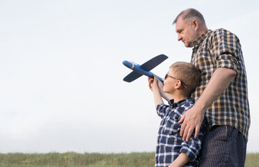 Father and son having fun in the field playing with an airplane