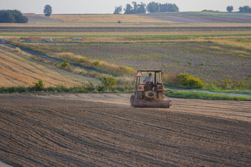 Ploughing a field at sunset with a tractor and plough, ready for crops on a farm © Bagatela