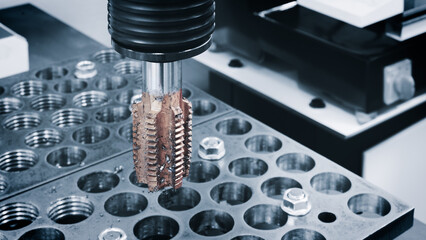 Part of a milling machine used to cut a piece of metal. The machine is surrounded by a number of...