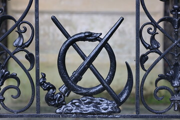 decorative metal fence with scythe, Ouroboros and extinguished torch close up