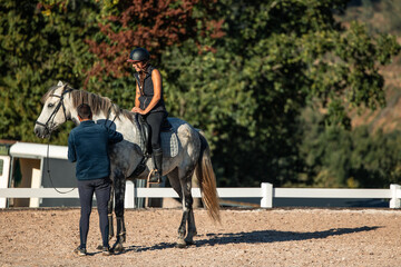 Riding instructor assists young student on horseback during a lesson at the equestrian center