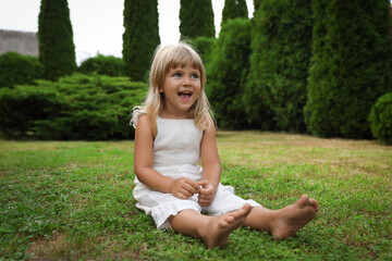 Fototapeta premium Barefoot little girl on green grass outdoors. Child enjoying beautiful nature