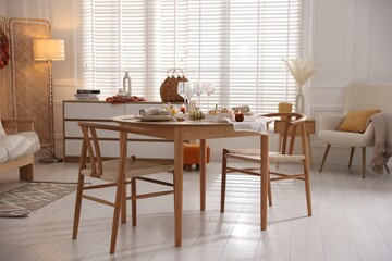 Stylish table setting with beautiful dishware and autumn decor in dining room