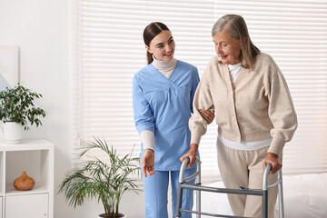 Fototapeta premium Nurse helping senior woman with walking frame in clinic