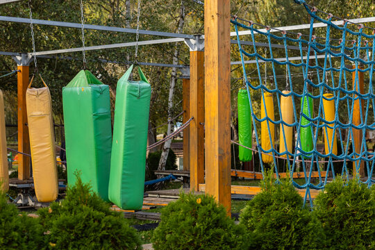 Colorful obstacle course with hanging cushions and net climbing area in outdoor adventure park. Physical challenge, sports entertainment, and outdoor activities
