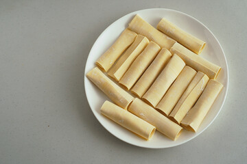 Uncooked tequeños arranged on a white plate