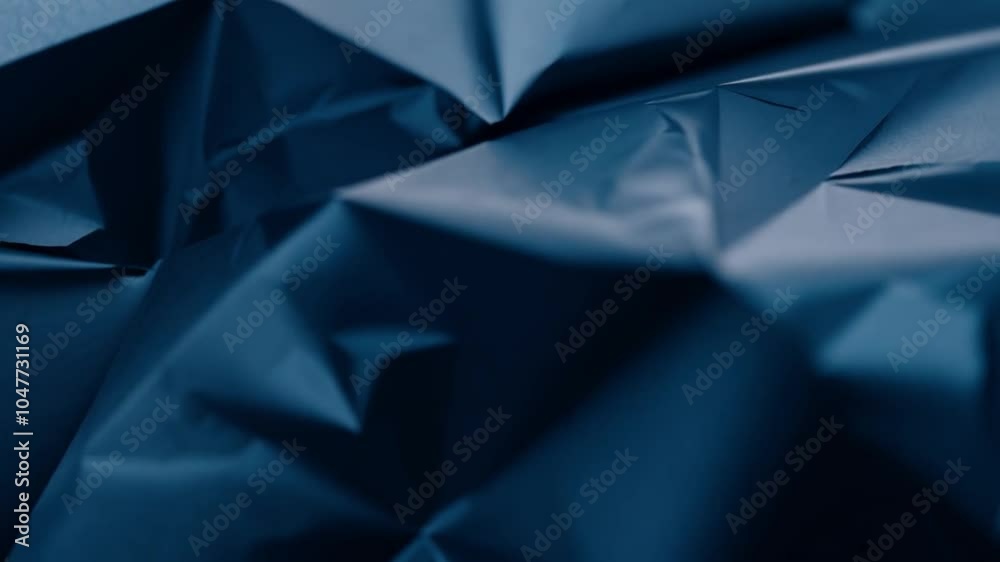 Aufkleber the crumpled dark blue paper exhibits intricate creases and folds, creating an abstract textural bac