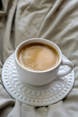 fotografia superior de xícara cheia de café sobre cama com tecido neutro e minimalista. com espaço livre para texto. ninguém. sem pessoas.