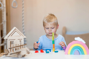A little boy of 2 years old is playing a developing logistics constructor. Children's wooden toys....
