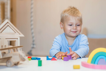 A little boy of 2 years old is playing a developing logistics constructor. Children's wooden toys....