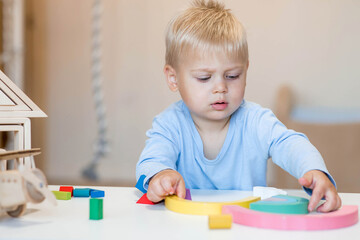 A little boy of 2 years old is playing a developing logistics constructor. Children's wooden toys....