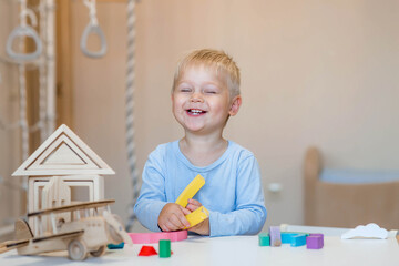 A little boy of 2 years old is playing a developing logistics constructor. Children's wooden toys....