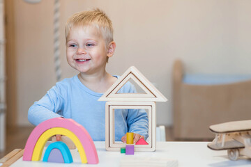 A little boy of 2 years old is playing a developing logistics constructor. Children's wooden toys....