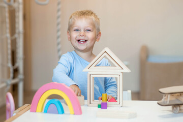 A little boy of 2 years old is playing a developing logistics constructor. Children's wooden toys....