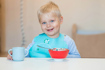 Baby food. Eating. Feeding the baby. A cute kid eats on his own with a spoon. Healthy eating. Family and children.