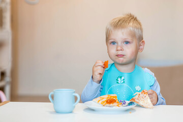 Unhealthy food for children. Eating. A cute 2-year-old kid eats pizza for lunch. Fast food. Family and children.