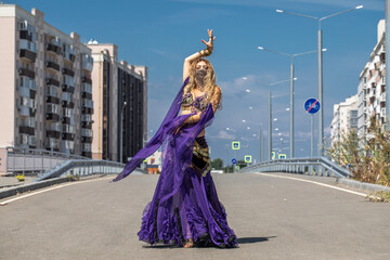 Obraz premium Sexy beautiful woman in a purple costume dances on the street
