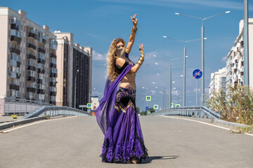 Naklejka premium Sexy beautiful woman in a purple costume dances on the street