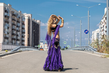 Obraz premium Sexy beautiful woman in a purple costume dances on the street