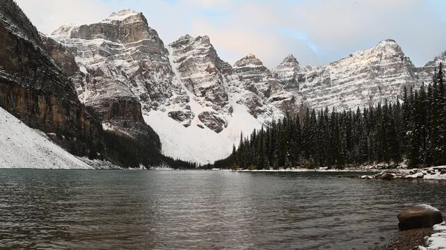 Lake Moraine at Ten Peak Valley at sunrise in Banff National Park, early autumn with snowy mountains and pine trees, rippling water