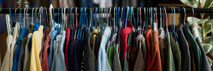 Header of row of hangers with secondhand casual apparel hanging along rack in modern thrift shop offering outdated things