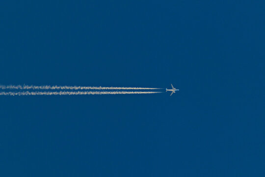 jetliner crossing the cloudless blue sky leaving a vapor trail.