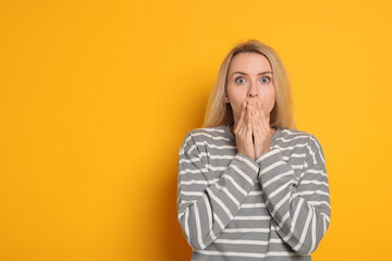 Portrait of scared woman on orange background, space for text