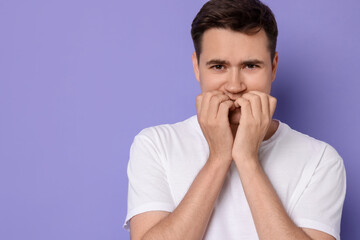 Portrait of scared young man on violet background, space for text