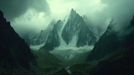 A majestic mountain peak shrouded in mist, with a valley leading up to it.
