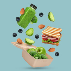 Lunch box, different food and bottle of juice in air on light blue background