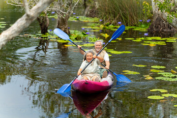 Happy Asian family senior couple kayaking in the river on summer holiday vacation. Healthy elderly people enjoy and fun outdoor active lifestyle travel nature, sport and rowing a boat in the lake.