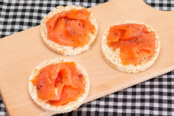 Tasty Rice Cake Sandwiches with Fresh Salmon Slices on Cutting Board - Top View. Easy Breakfast and Diet Food. Crispbread with Red Fish. Healthy Dietary Snack