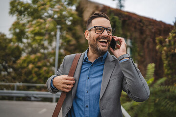 Smiling adult man businessman stand on the terrace and have phone call