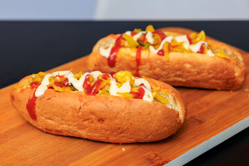Two hot dogs with ketchup and mustard on a wooden table