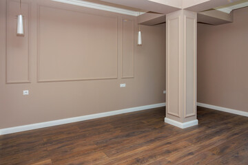 A large empty room with a white wall and a brown wooden floor