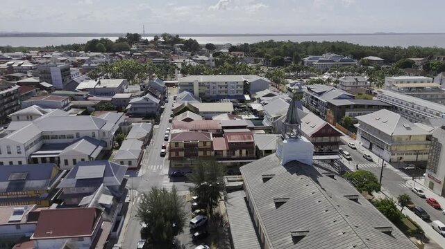 Drone flies over Cathedrale Saint-Sauveur toward Place des Palmistes in Cayenne, French Guiana, France