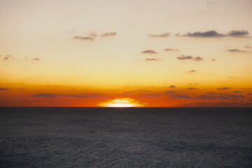 Obraz premium The sun slowly disappearing behind the horizon over the sea, creating a stunning sunset wallpaper.