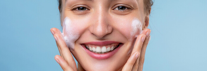 Facial wash. Young woman clean her face with a skin cleansing foam soap