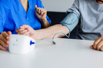 Close up view of young female doctor measuring blood pressure to senior patient with hypertension...