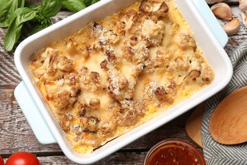 Tasty baked cauliflower, sauce and products on wooden table, flat lay