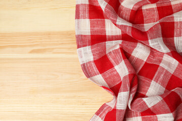 Obraz premium Crumpled tablecloth with checkered pattern on light wooden table, top view. Space for text