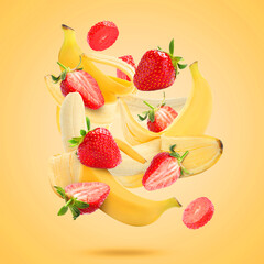 Fresh bananas and strawberries falling on golden background