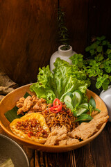 Delicious fried noodles with crispy chicken and spicy sambal, served in a rustic style that...