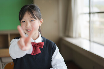 ピースサインをする笑顔の日本人女子中学生