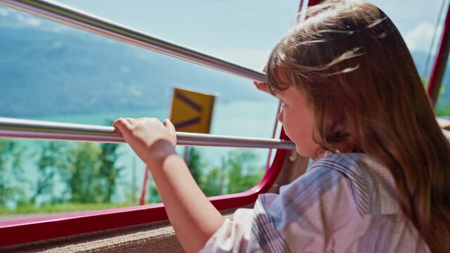 Little girl ride in the famous red rotary steam train leaving the town of Brienz in the Swiss Alps along the alpine meadows to the top of a mountain in summer. Switzerland