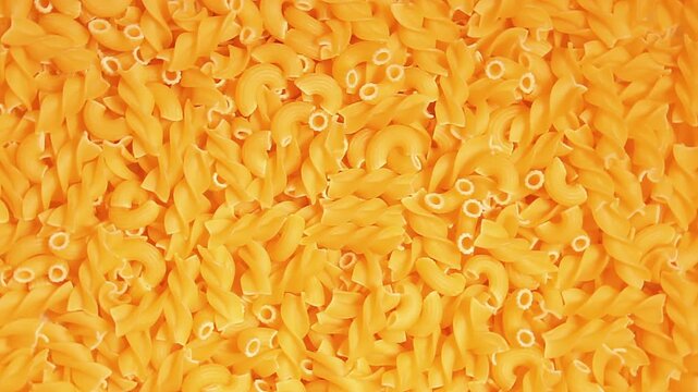 Uncooked Fusilli and Chifferi Rigati Pasta - Top View. Fat and Unhealthy Food. Classic Dry Macaroni, Slowly Rotating Background. Raw Different Macaroni Pasta Texture - Rotate Right