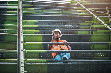 Building, construction and black woman on site with radio for advice, discussion or planning in architecture. Developer, contractor or female project manager at scaffolding for wireless communication