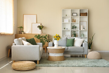 Comfortable sofas and wild flowers in vase on coffee table in interior of living room